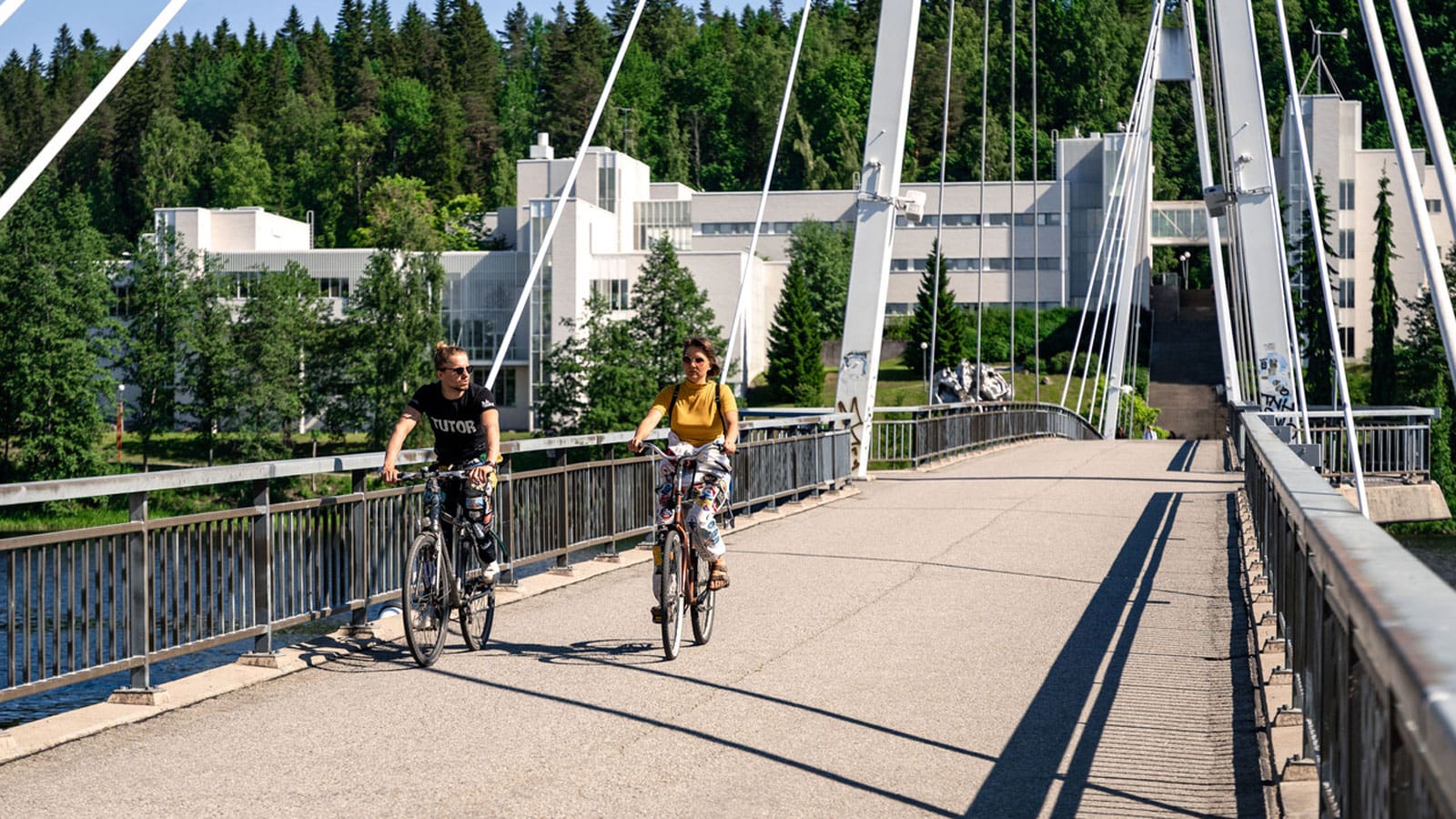Two persons cycling on the bridge.