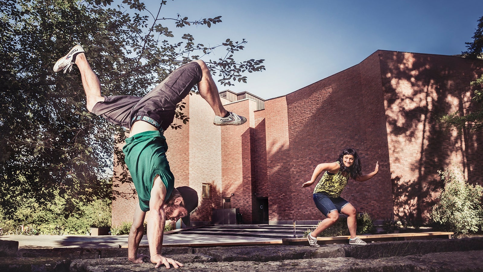 Two persons in sporty positions in front of Jyväskylä’s University