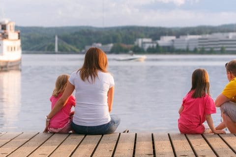 Kaksi aikuista ja kaksi lasta istuu laiturilla Jyväskylän Lutakon satamassa.