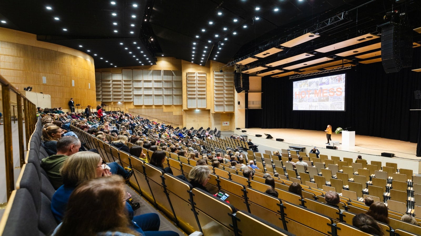 Paljon ihmisiä kuuntelemassa esitystä auditoriossa.