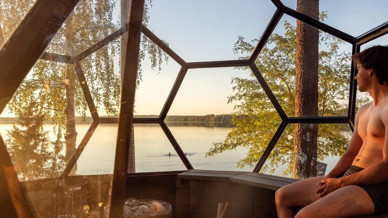 Henkilö istuu iglusaunassa järven äärellä