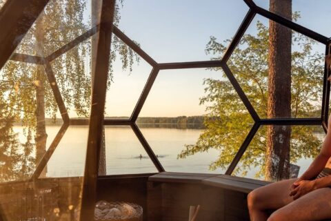 Henkilö istuu iglusaunassa järven äärellä