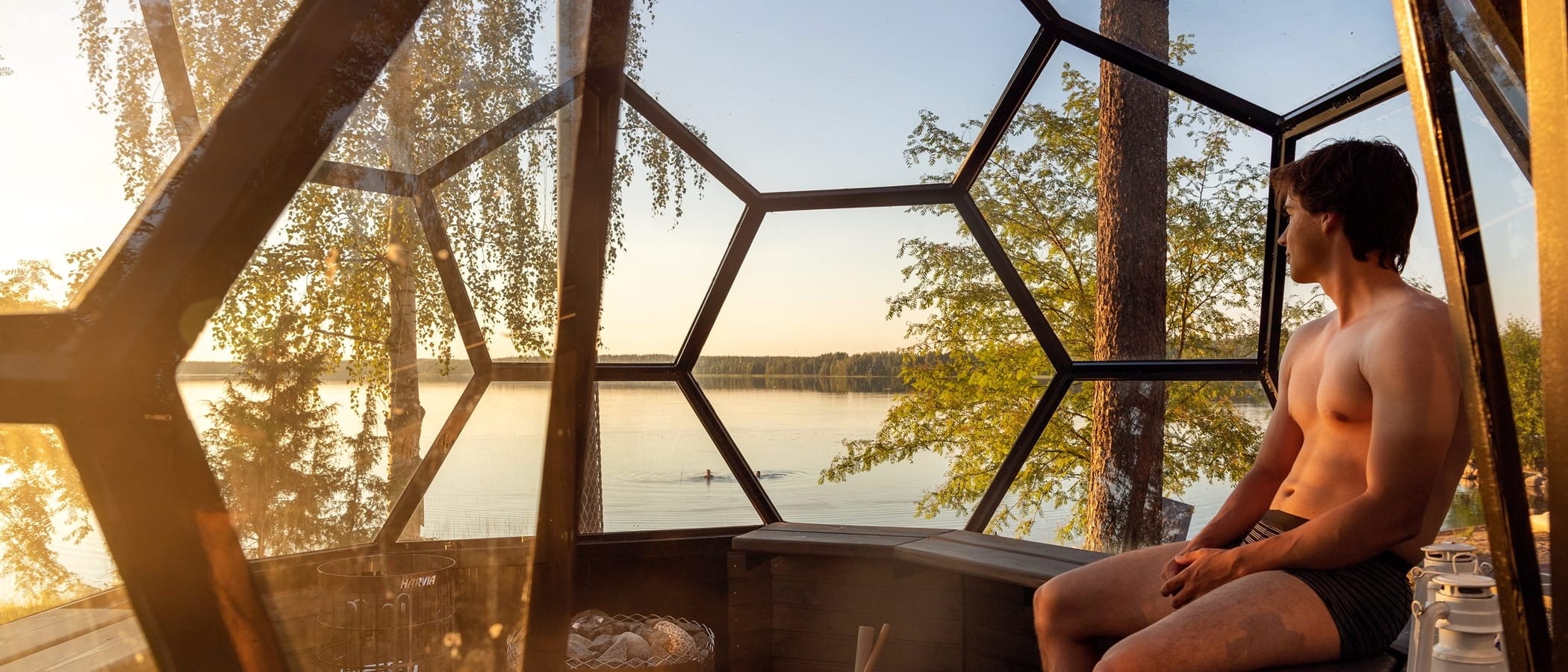 Henkilö istuu iglusaunassa järven äärellä