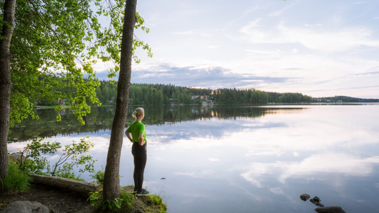 Henkilö seisoo järven rannalla.
