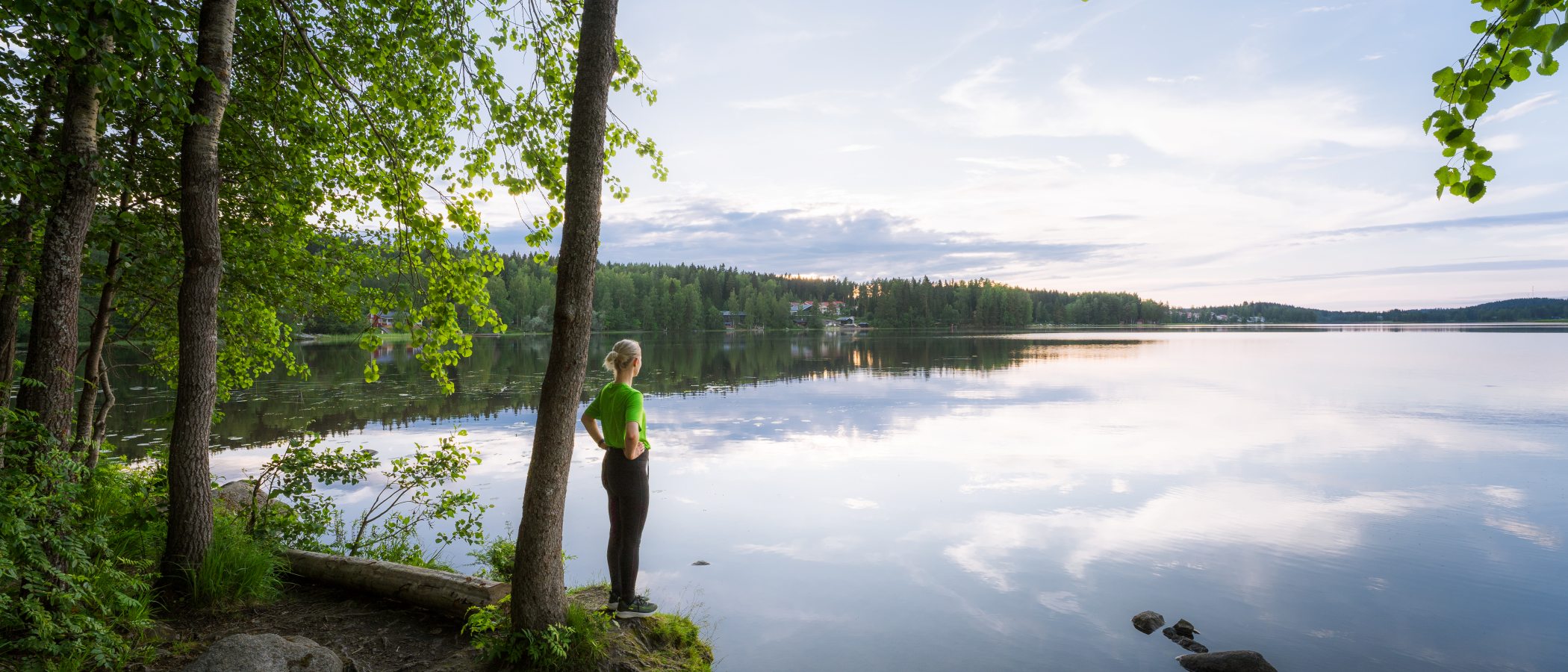 Henkilö seisoo järven rannalla.
