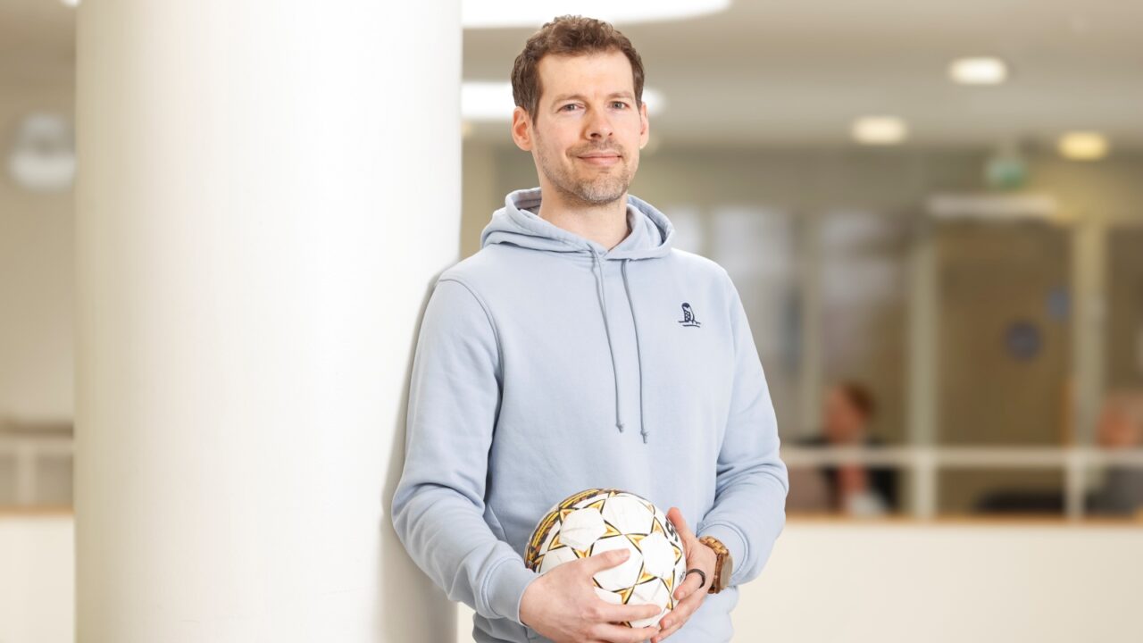 A person is standing with a soccer ball in their hand.