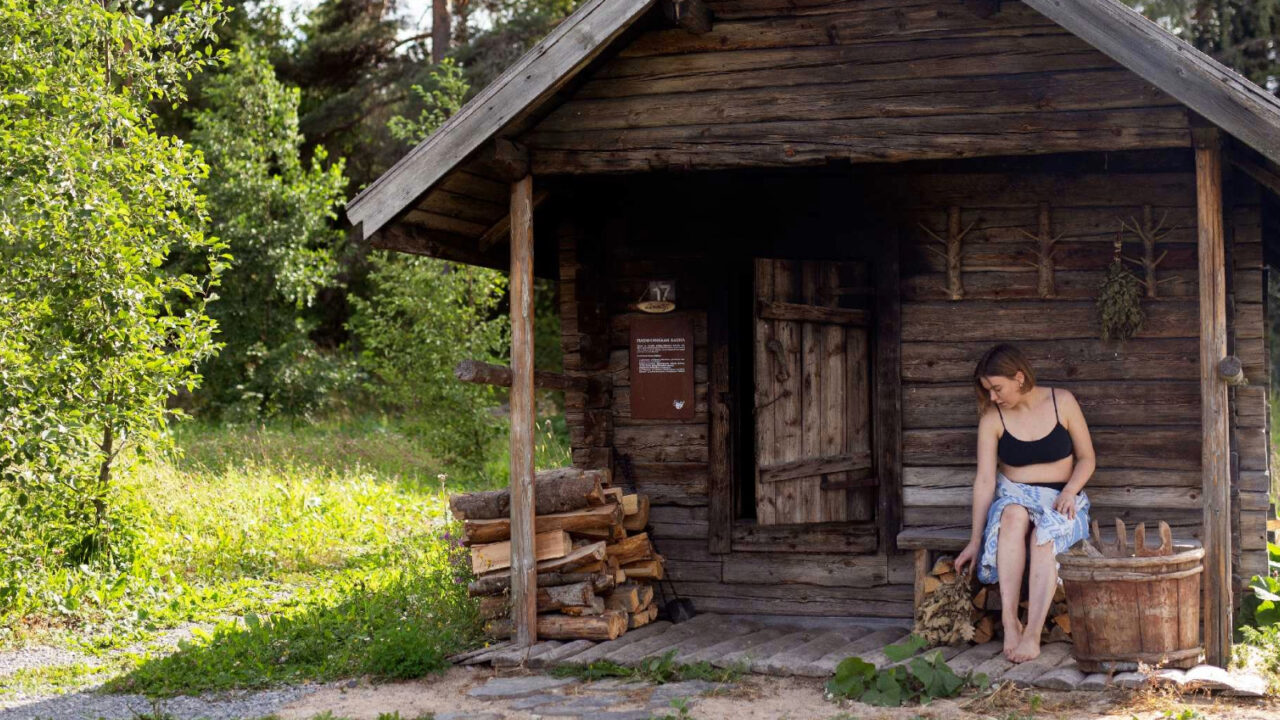 A person sitting in front of smoke sauna at Sauna Village.