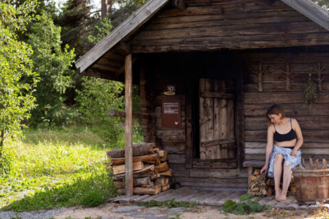 A person sitting in front of smoke sauna at Sauna Village.