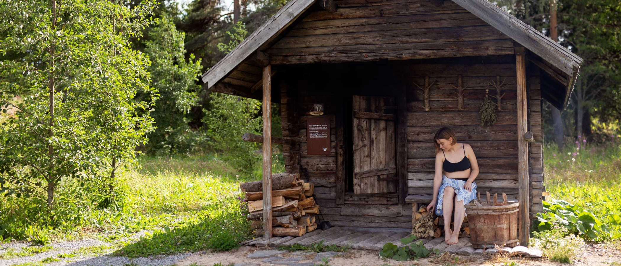 A person sitting in front of smoke sauna at Sauna Village.