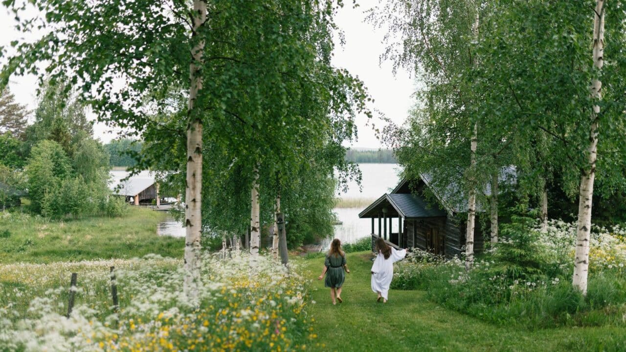 Zwei Personen gehen auf einem Grasweg in Richtung See.