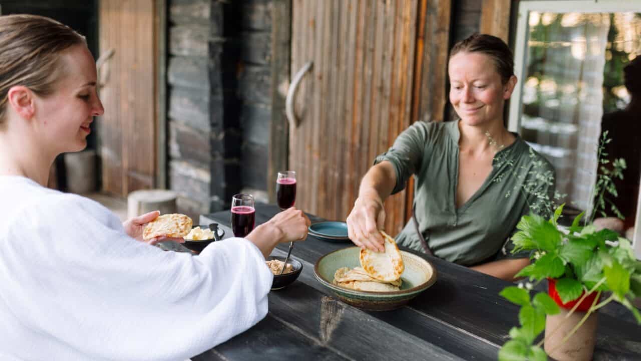 Henkilöt syömässä savusaunan terassilla Ranta-Keurulan matkailumaatilalla.