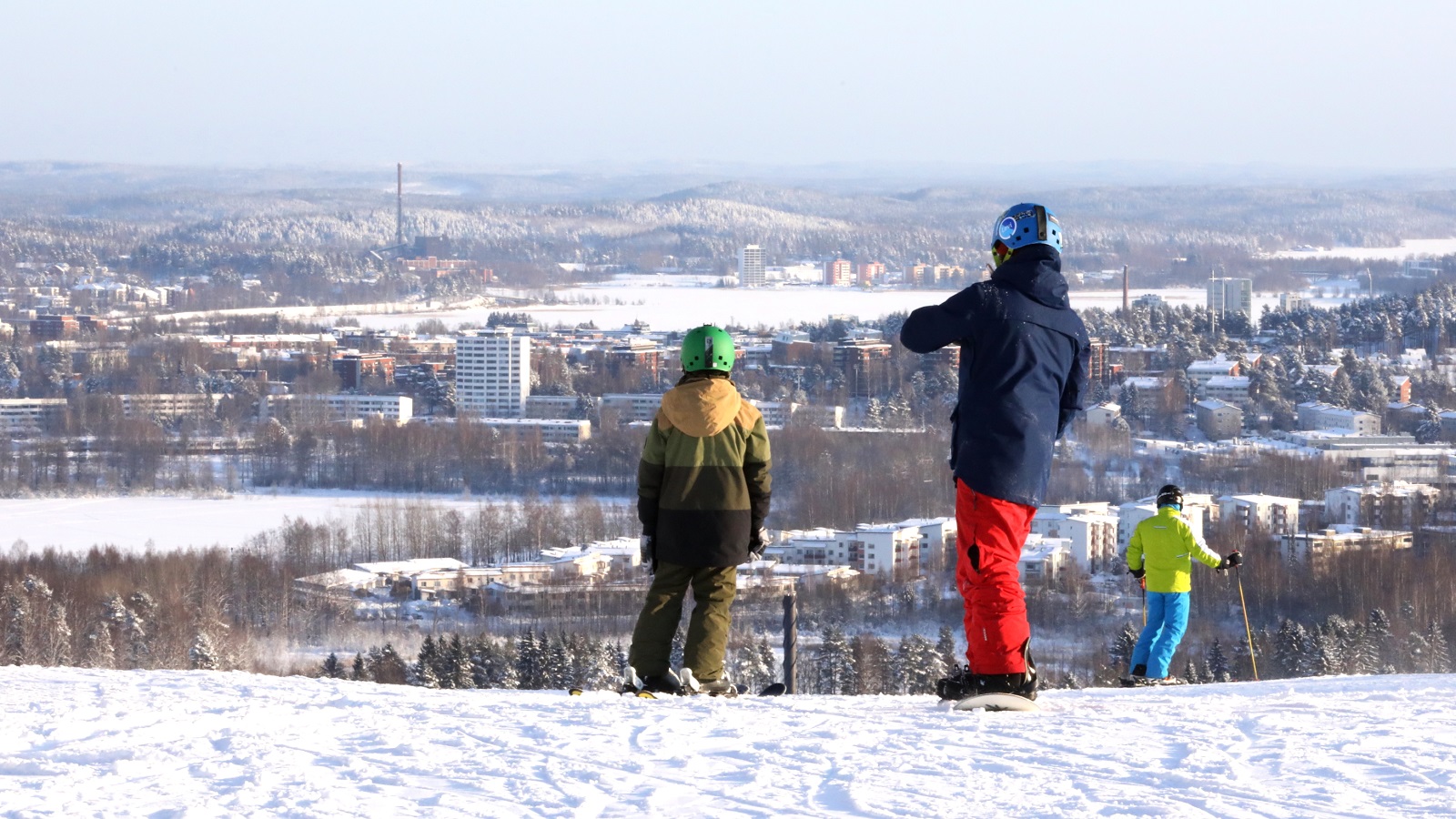 Isä ja lapsi laskettelemassa vuoren laella talvella.