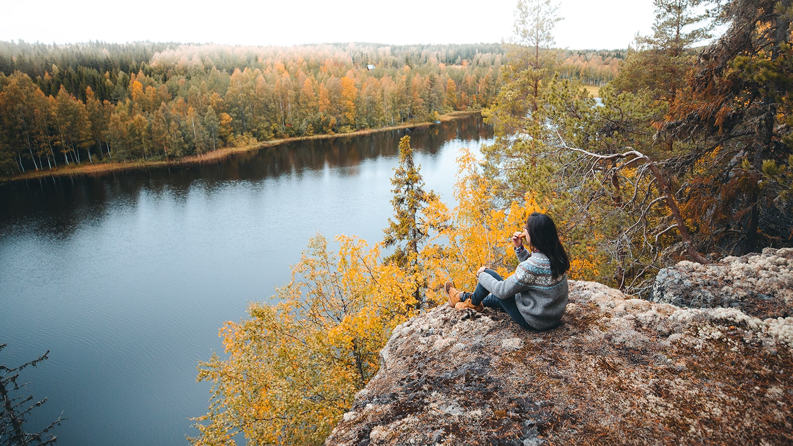 Person is sitting at a cliff watching the view at Lomaseutu