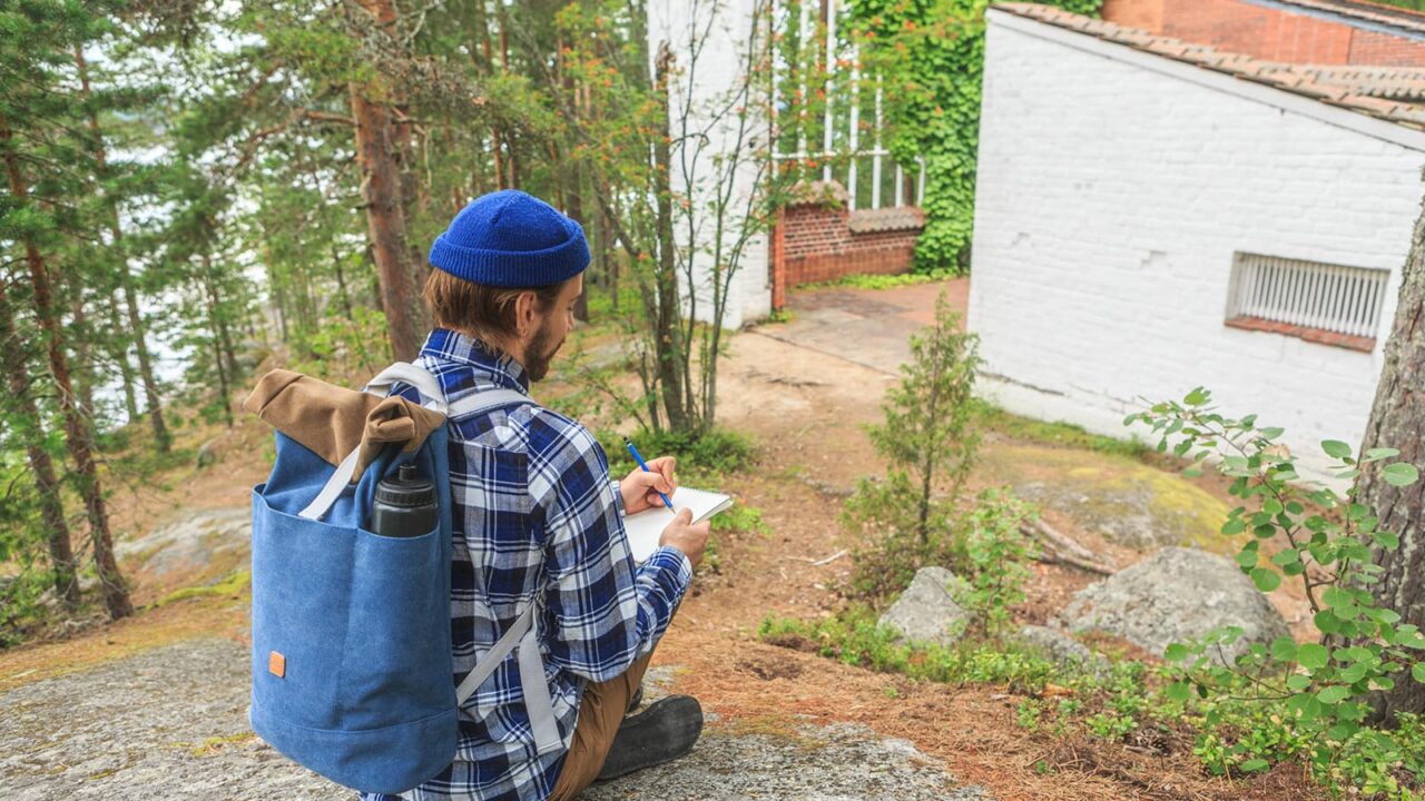 Henkilö kirjoittamassa kalliolla Muuratsalon koetalon vieressä