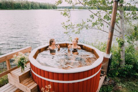Dos personas están sentadas en un jacuzzi junto al lago.
