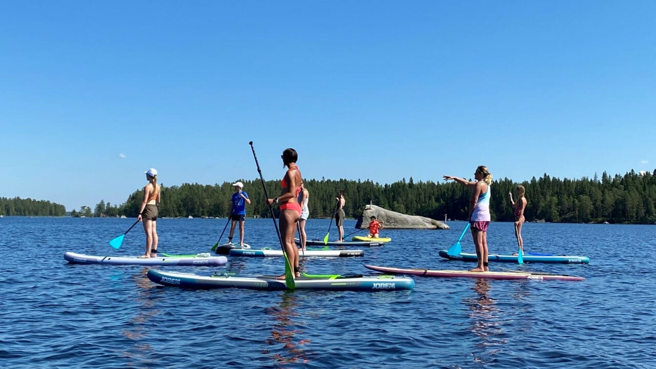 Ihmisiä seisomassa Sup-laudoillansa järvellä
