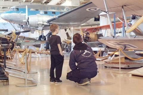 Lapsi ja aikuinen katsovat lentokonetta Suomen Ilmavoimamuseossa.
