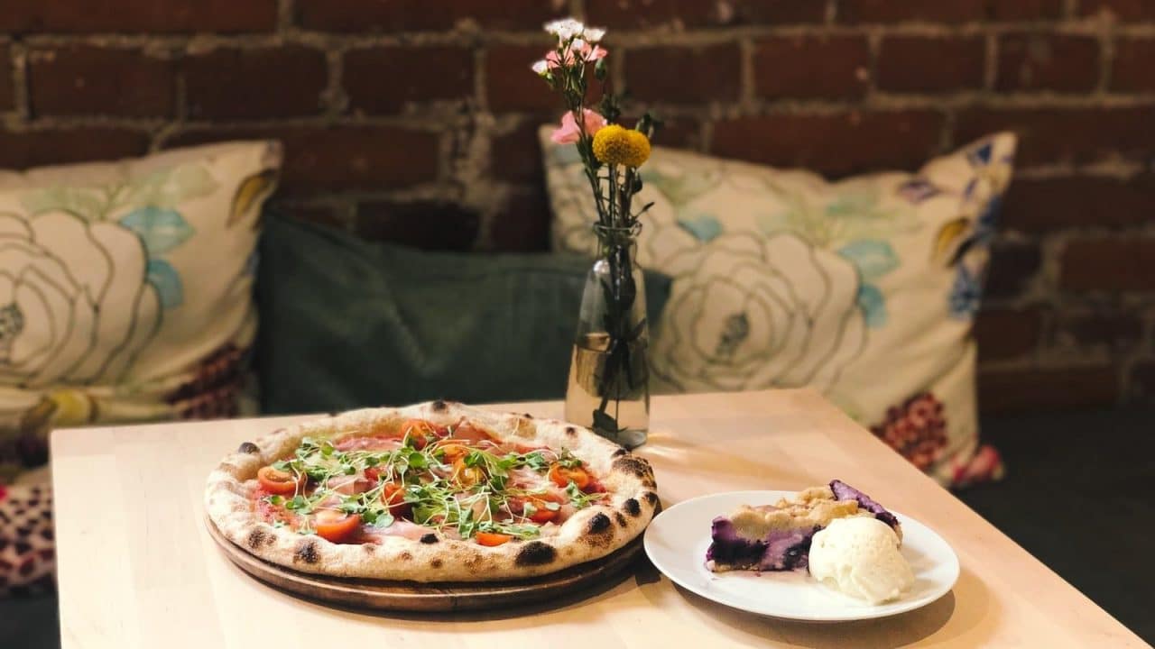 Ravintolan pöydällä on artesaanipizza sekä kakkupala
