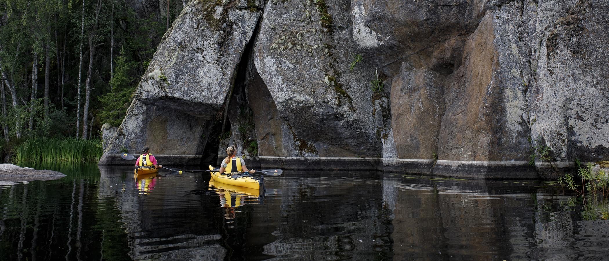 Kaksi henkilö ihastelemassa kalliota kajakista