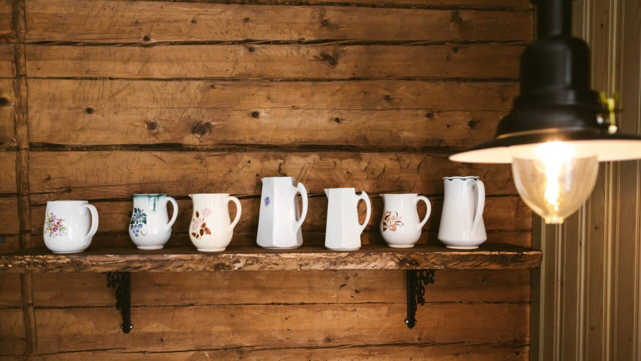 Old porcelain jugs lined up on a wall shelf.