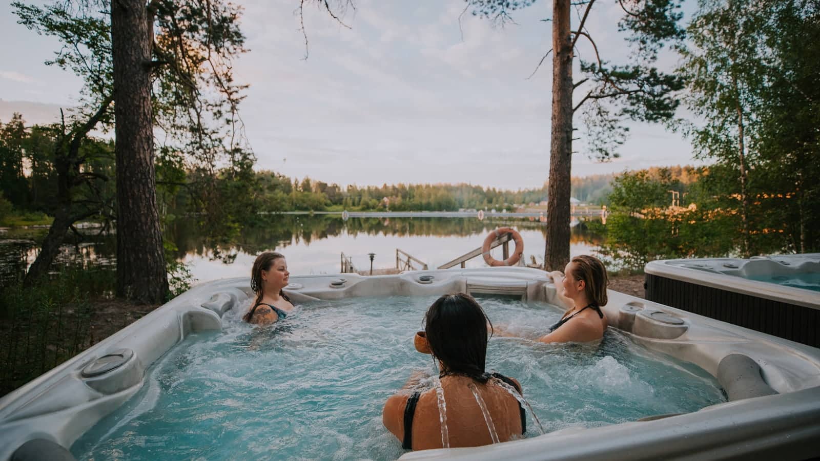Drei Personen sind im Whirpool neben einem See