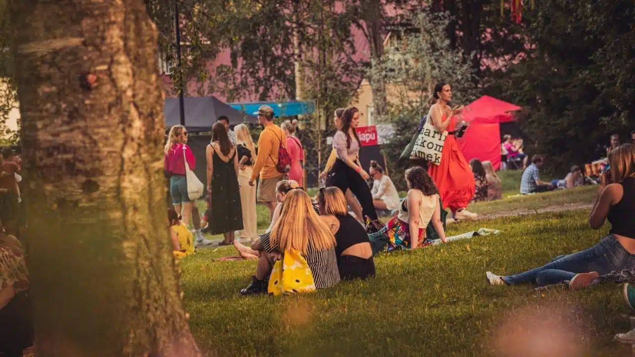 People sitting and walking in Lounaispuisto in Jyväskylä at the Puistojuhla -festival.