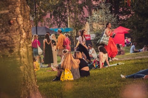 Ihmisiä Jyväskylän Lounaispuistossa kesällä, istumassa ja kävelemässä Puistojuhlassa.