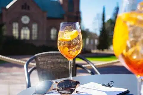 Jyväskylän kirkkopuistossa terassipöytä, jossa aurinkolasit sekä kaksi Aperol Spritz-cocktailia.