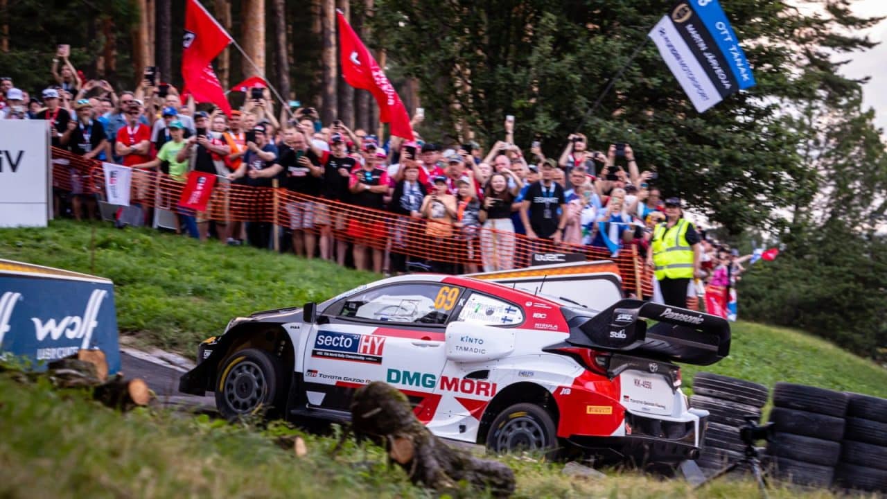 Pildil on ralliauto ja taustal ergutavad inimesed.