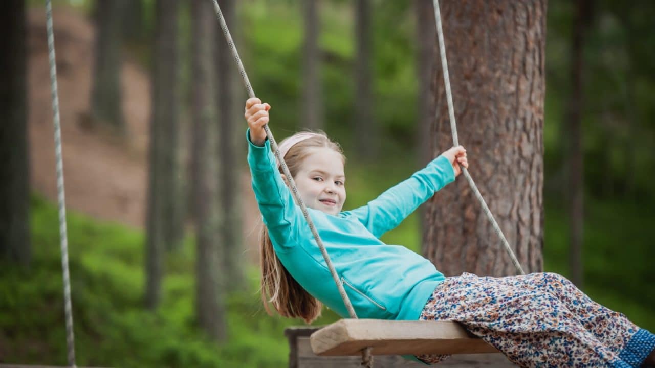 Lapsi keinumassa metsämaisemassa