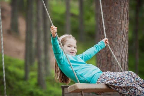 Lapsi keinumassa metsämaisemassa