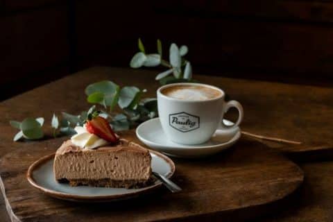 Piece of cake and a coffee mug placed on a wooden table.