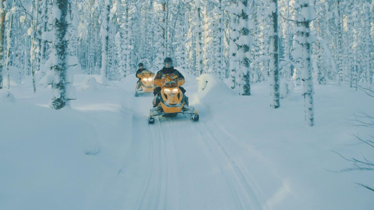 Snowmobilers in a winter landscape in Lakeland Finland.