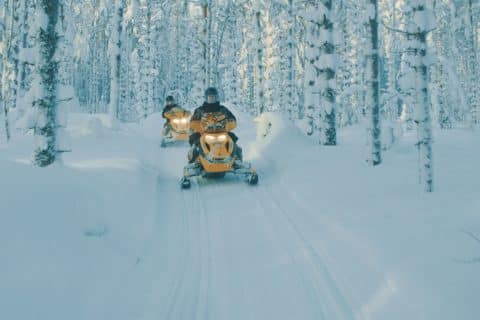 Snowmobilers in a winter landscape in Lakeland Finland.