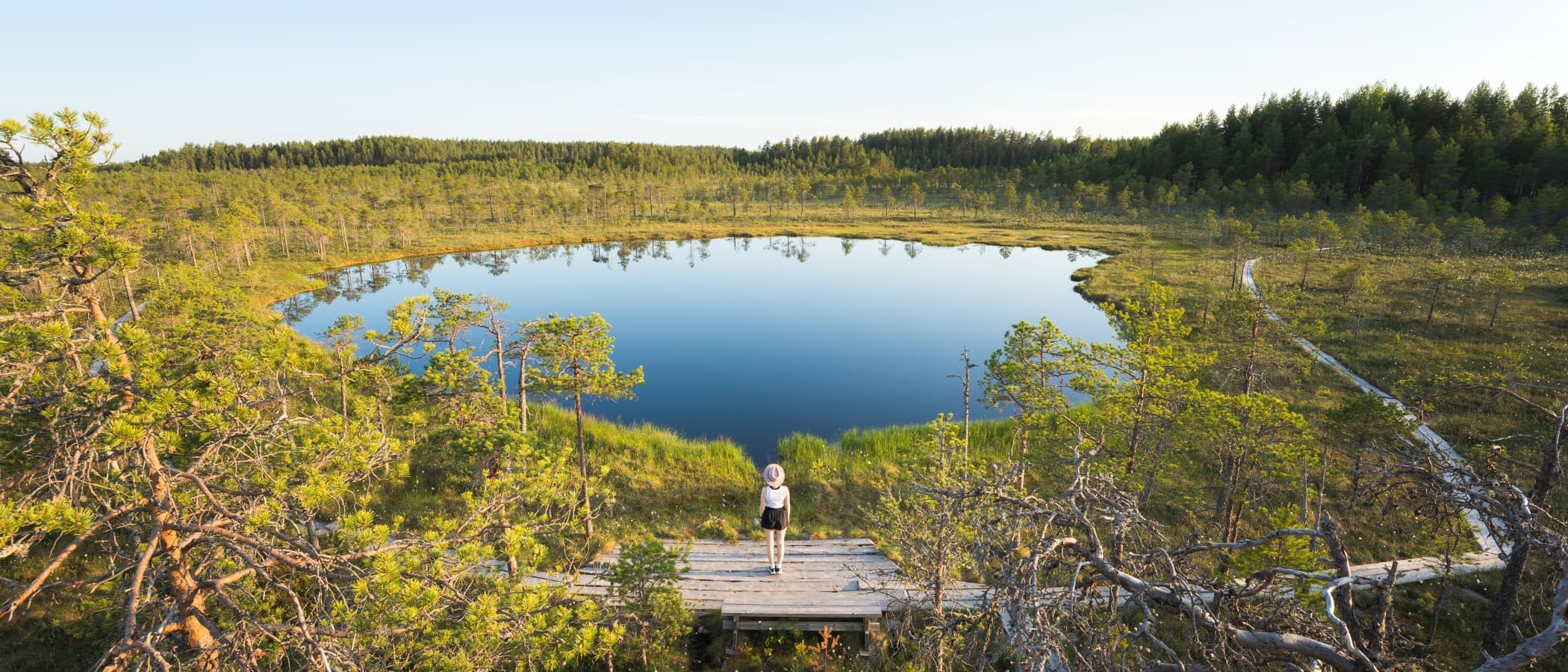 Henkilö seisoo Leivonmäen kansallispuistossa Kirveslammen rannalla.