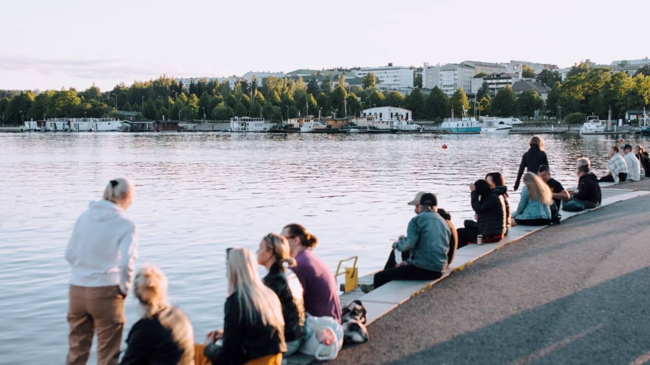 Ihmisiä istuu Lutakon satamassa.