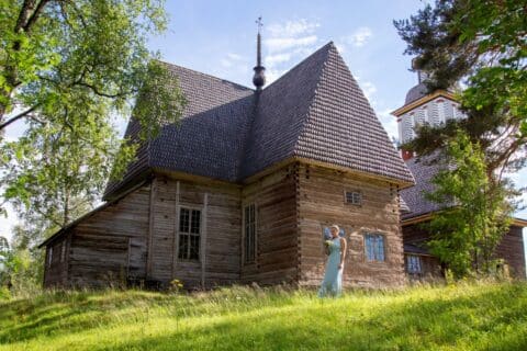 A person stands in front of the old church in Petäjävesi.