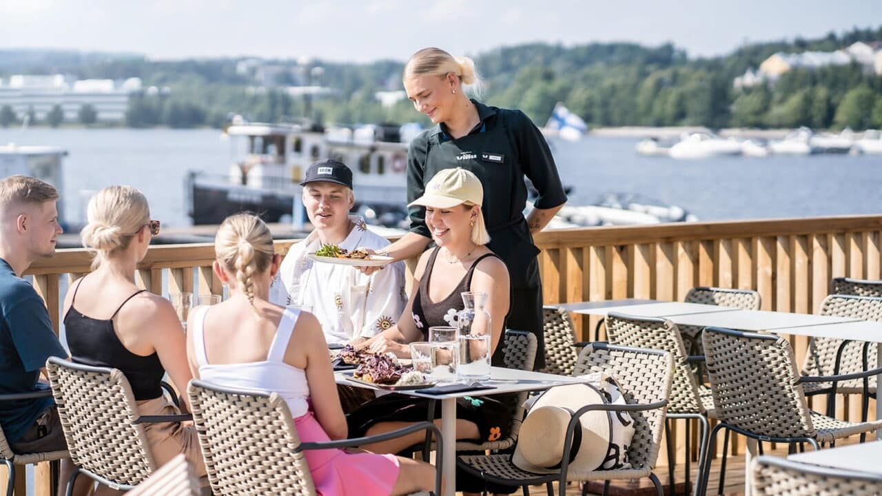 Tarjoilija tarjoilemassa asiakkaille ruokaa ravintolassa.