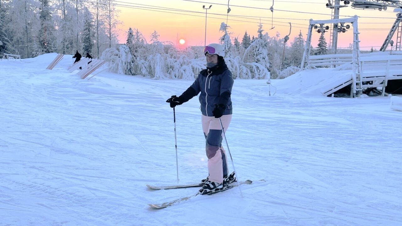 Henkilö laskettelusukset jalassa laskettelurinteen huipulla.
