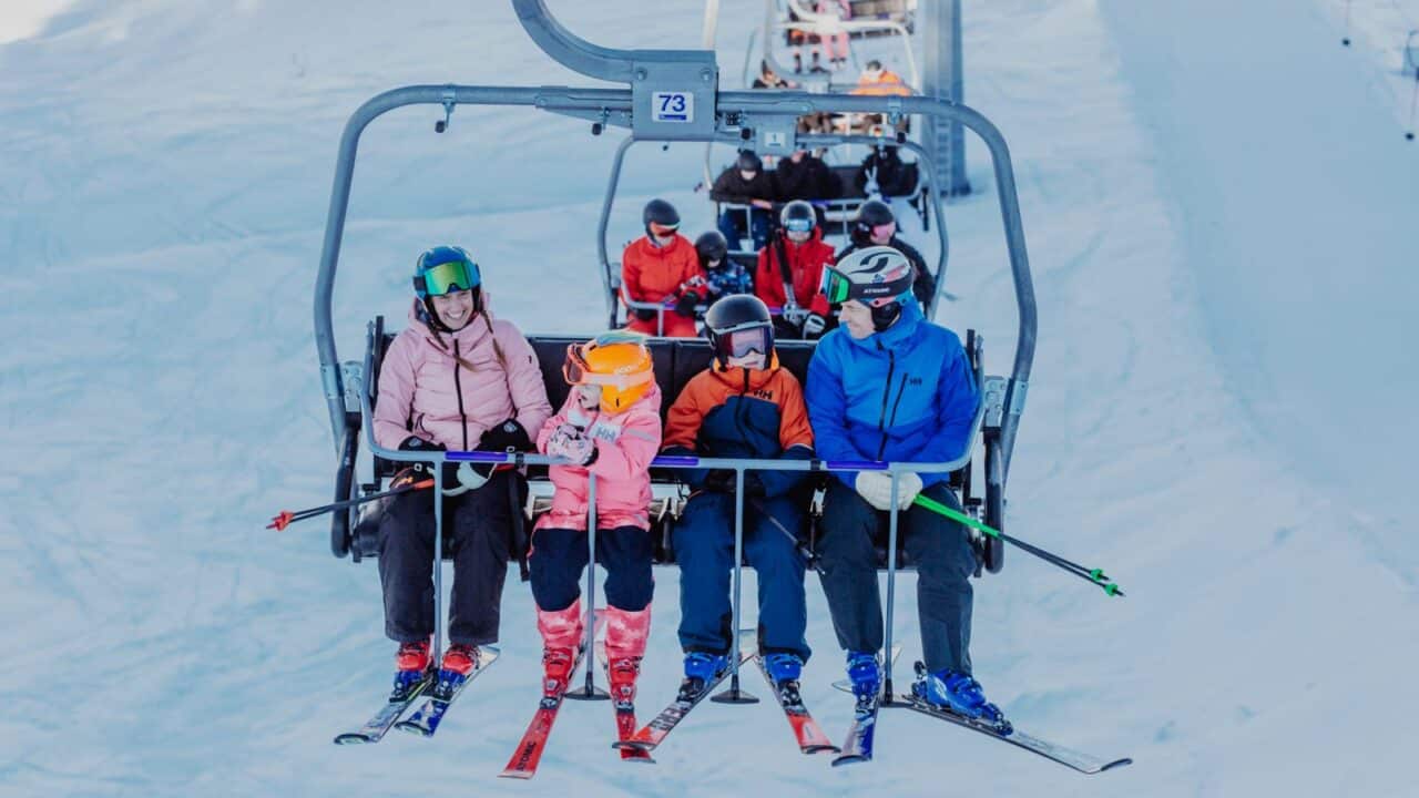 Two adults and two kids on a chairlift.