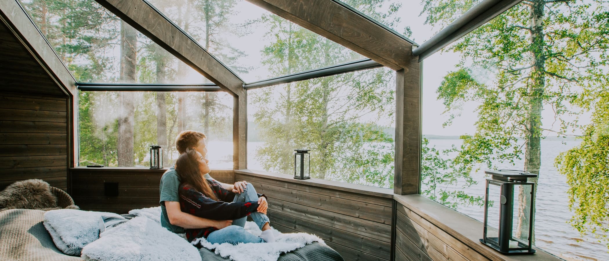 Two people sit on a glass igloo bed.