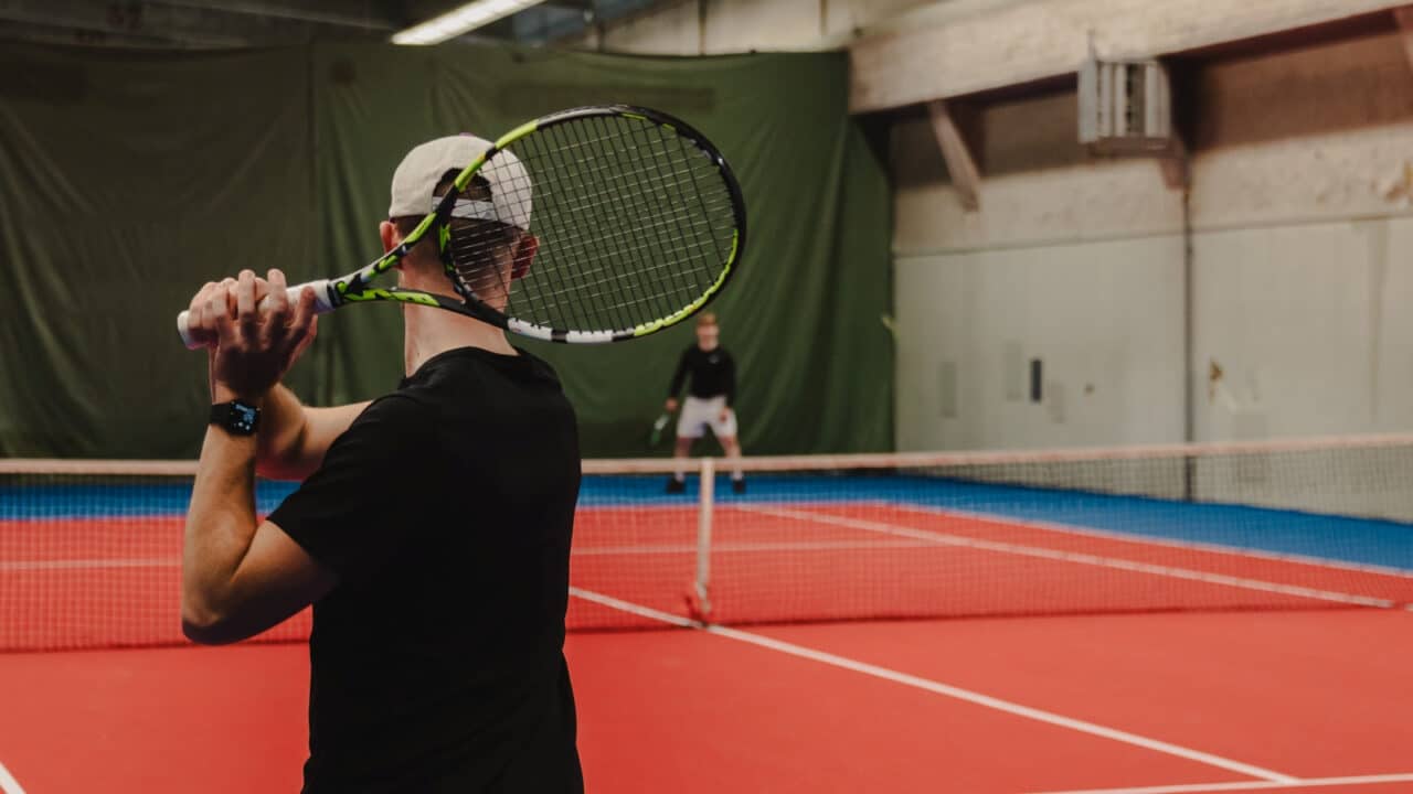 Kaksi henkilöä pelaamassa tennistä.