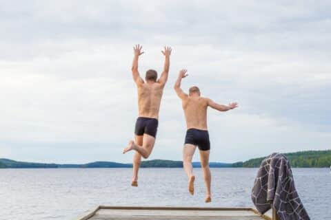 Kaks inimest hüppavad tekilt vette.