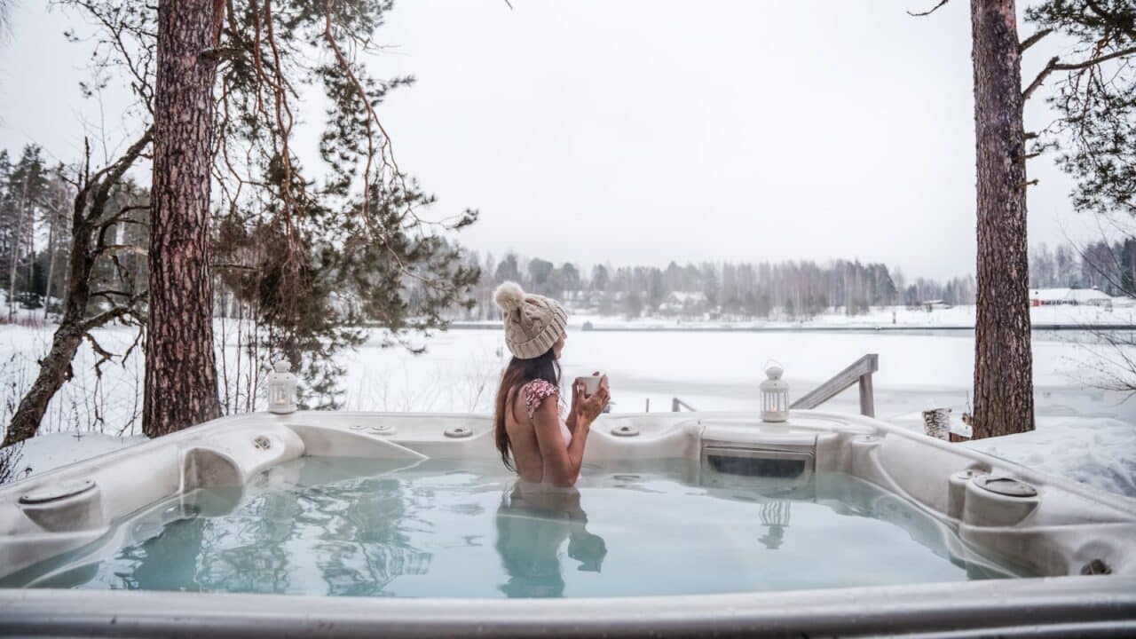 Eine Person entspannt sich in einem Freibad in einer Winterlandschaft.