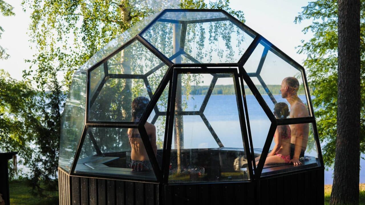 People admiring the lake view from an igloo sauna.