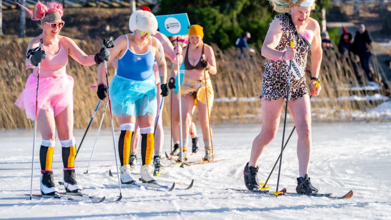 Ihmiset hiihtämässä hauskat asut päällä Simmarihiihto-tapahtumassa.