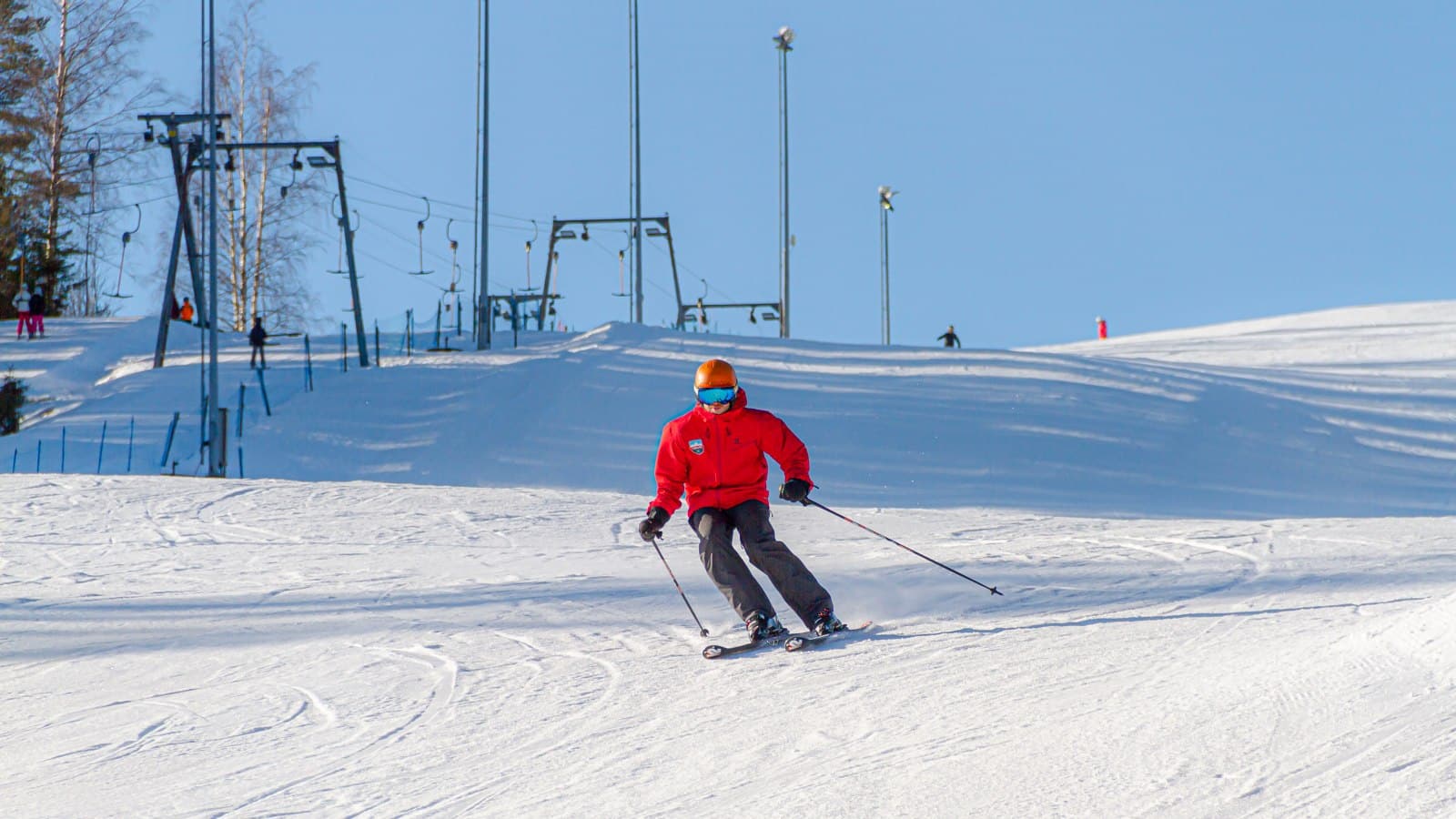 A person in a red jacket skiing down a slope.