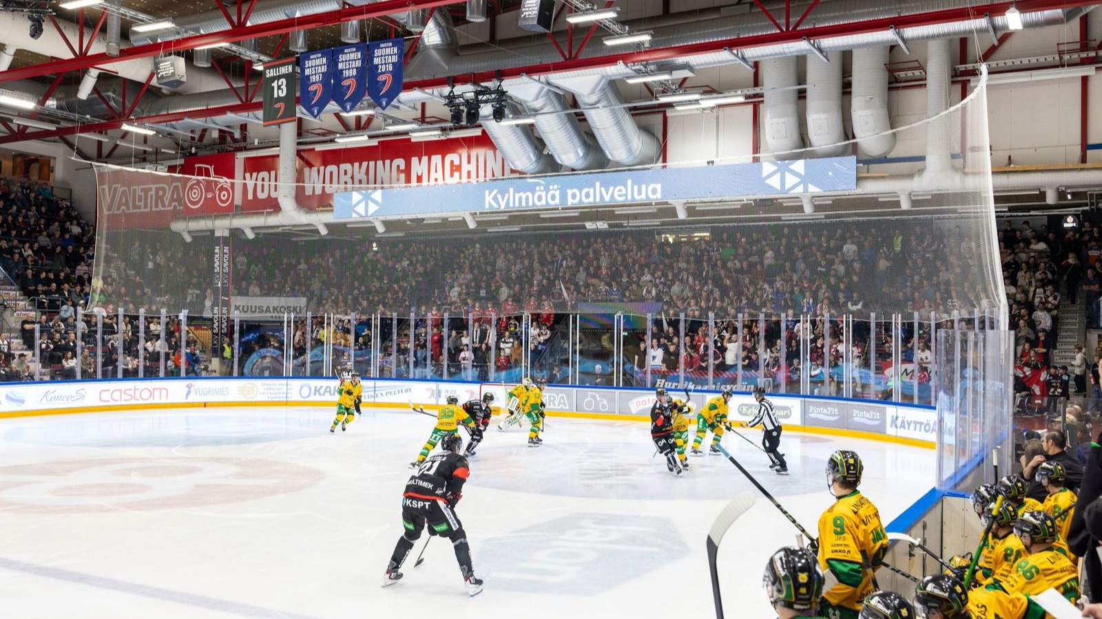 Jääkiekon pelaajat luistelevat jäähallin jäällä.