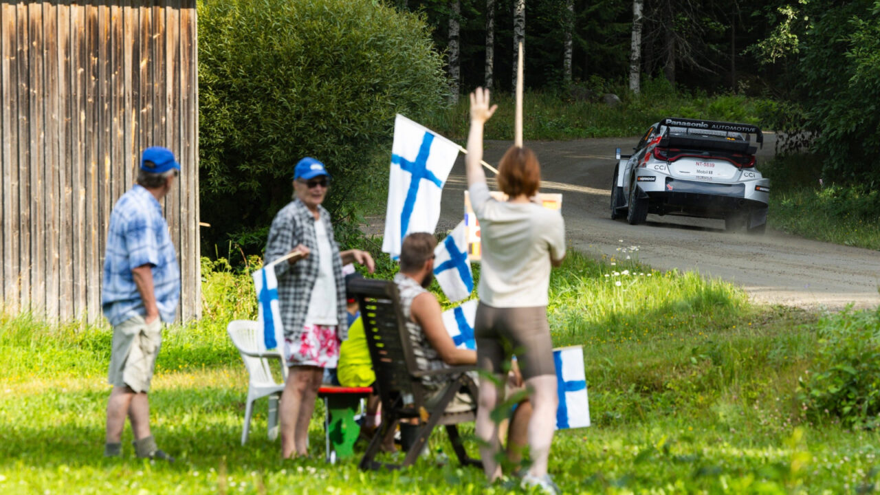 People cheering rally drivers along the rally route.