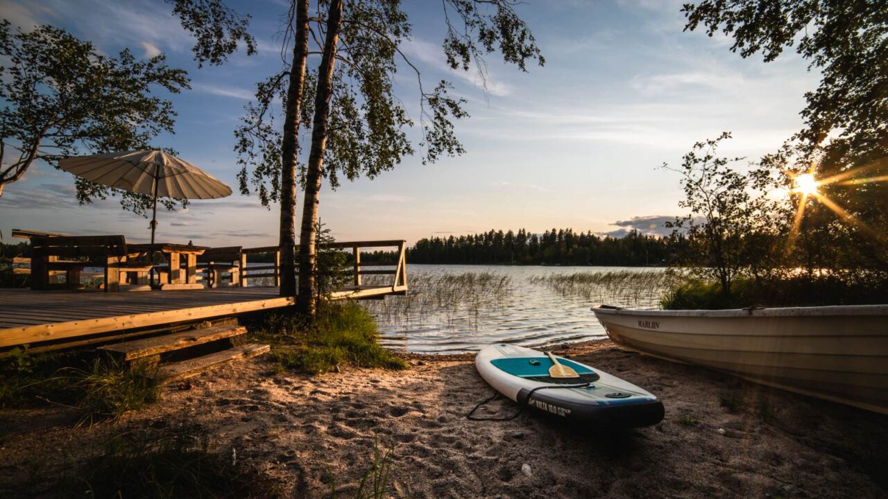Ranta ja sup-lauta kesällä auringonlaskun aikaan.